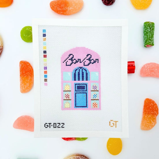 Needlepoint canvas design of a colorful candy shop with 'BonBon' text, surrounded by candy on a white background.
