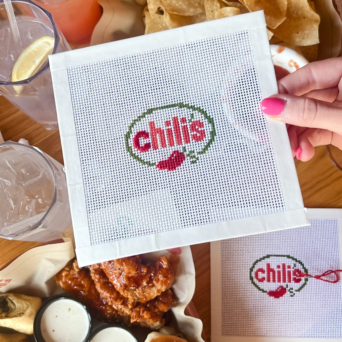 Spicy Restaurant needlepoint canvas held over a table with food and drinks.